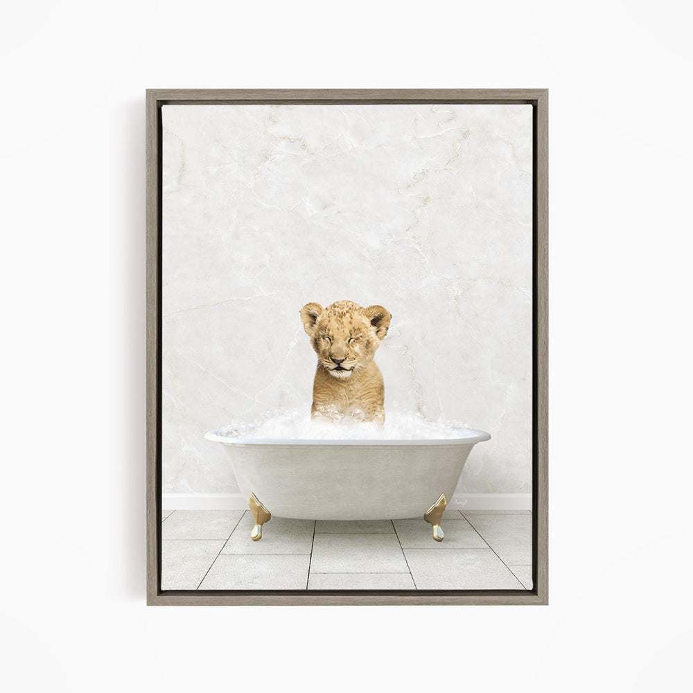 A young lion cub sitting in a white bathtub filled with water, looking up at the camera with a playful expression.