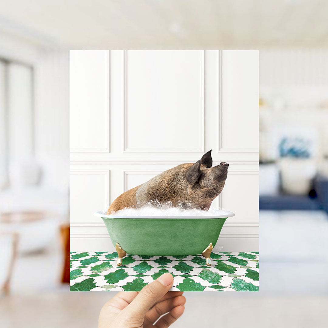 A hand holds up a framed image of a pig sitting in a green bathtub filled with bubbles, surrounded by a patterned floor.