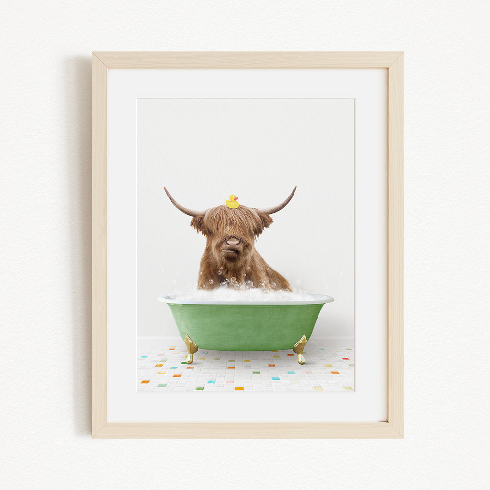 A brown cow with long horns is sitting in a green bathtub, with a yellow rubber duck perched on its head.