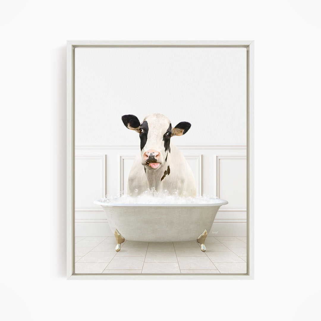 A black and white cow is sitting in a white bathtub filled with water, creating a whimsical and humorous scene.