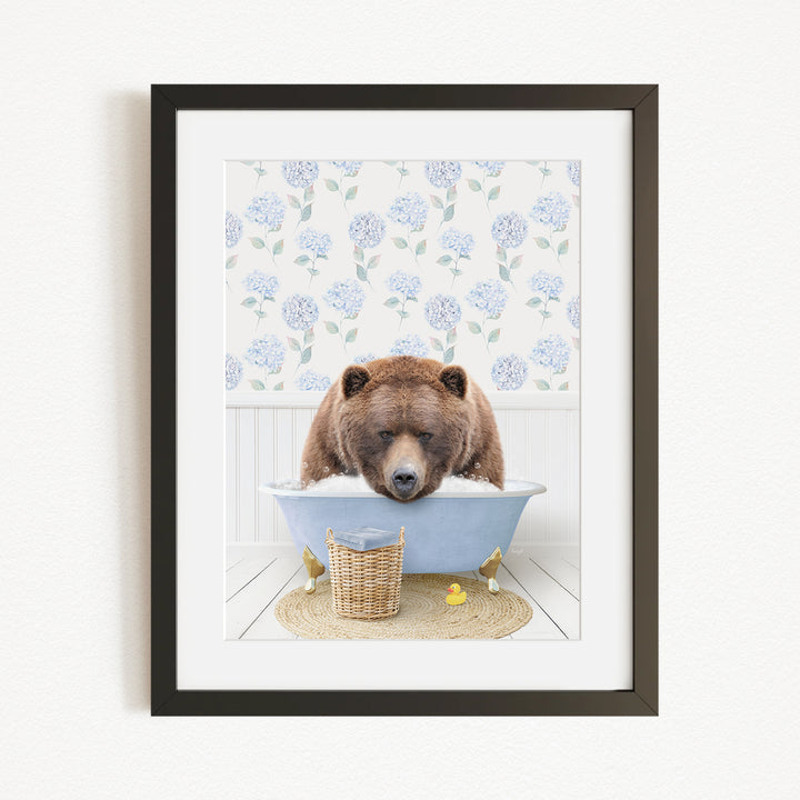 A brown bear is sitting in a blue bathtub filled with water, surrounded by a wicker basket and yellow rubber ducks.