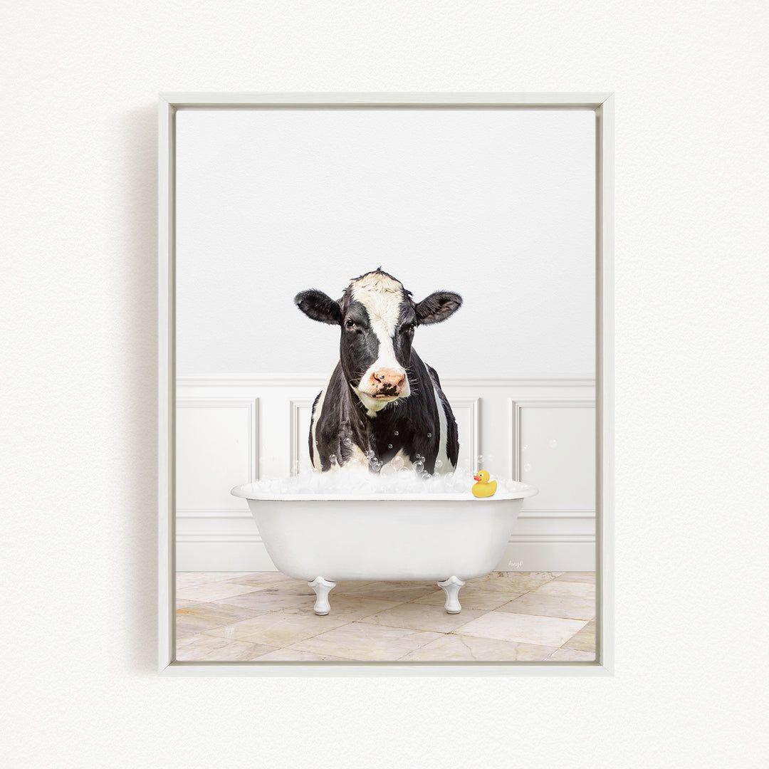 A black and white cow is standing in a white bathtub filled with water, with a rubber duck floating in the water.