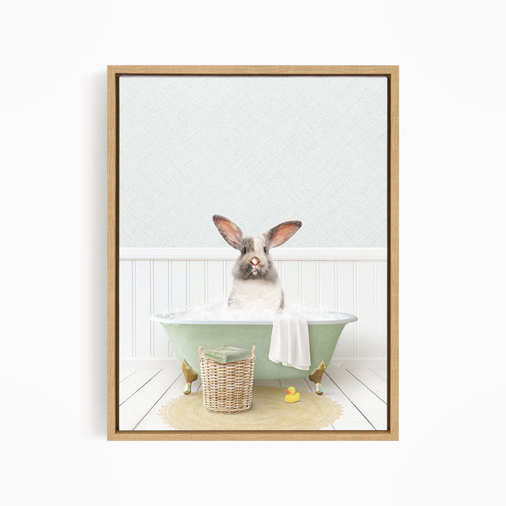 A white and brown rabbit sitting in a green bathtub filled with bubbles, surrounded by a basket of bath toys and a yellow rubber duck.