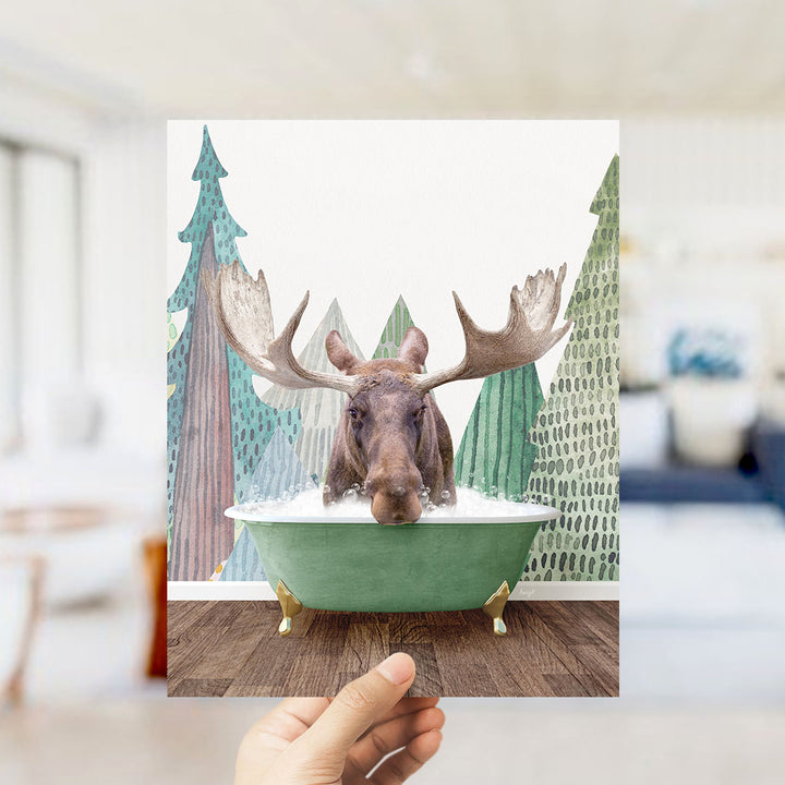A moose with large antlers is sitting in a green bathtub, surrounded by a winter landscape with trees and snow.