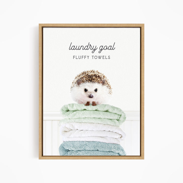 A framed image of a hedgehog sitting atop a stack of fluffy towels, with the text "laundry goal FLUFFY TOWELS" written above it.