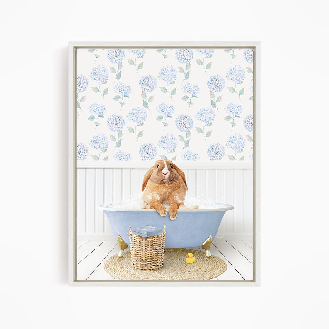 A brown rabbit sitting in a blue bathtub filled with water, surrounded by a wicker basket and a yellow rubber duck.