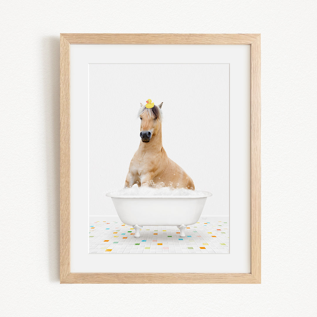 A brown horse is sitting in a white bathtub filled with bubbles, with a rubber duck perched on its head.