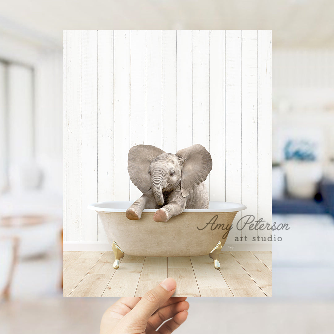 a hand holding a photo of an elephant in a bathtub