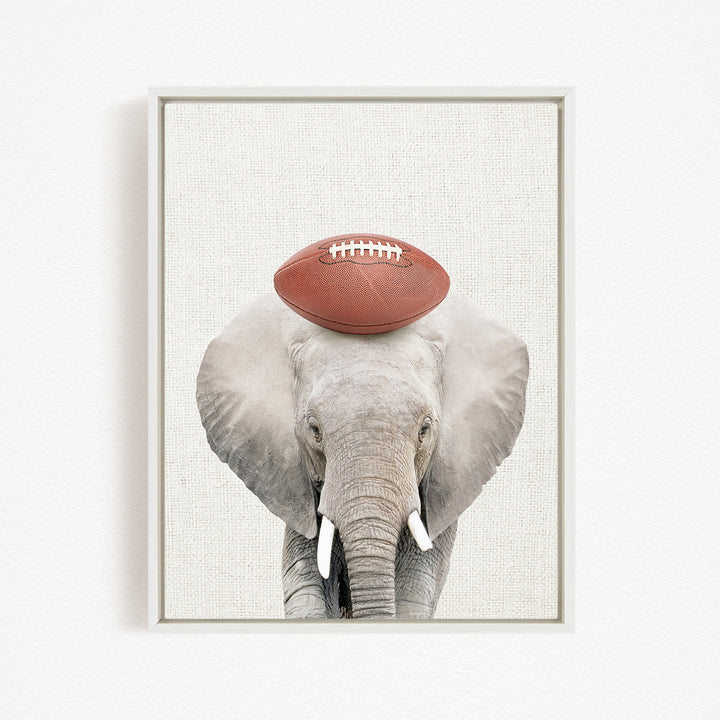 A gray elephant with a red football resting on its head.