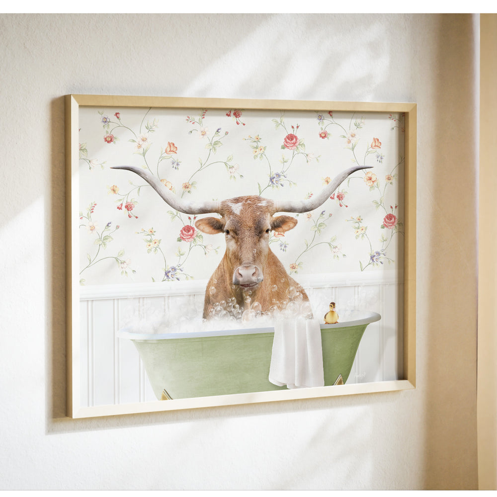 A framed image of a brown cow with large horns sitting in a green bathtub filled with bubbles, against a floral wallpaper background.