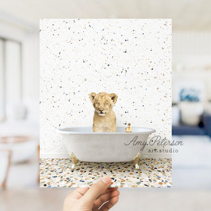 a hand holding a card with a picture of a baby lion in a bathtub