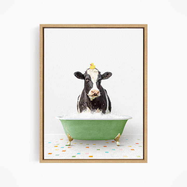 A black and white cow is sitting in a green bathtub filled with water, with a yellow rubber duck perched on its head.