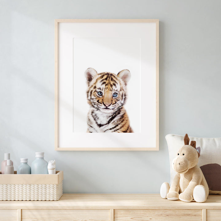 a framed picture of a tiger cub sitting on a dresser