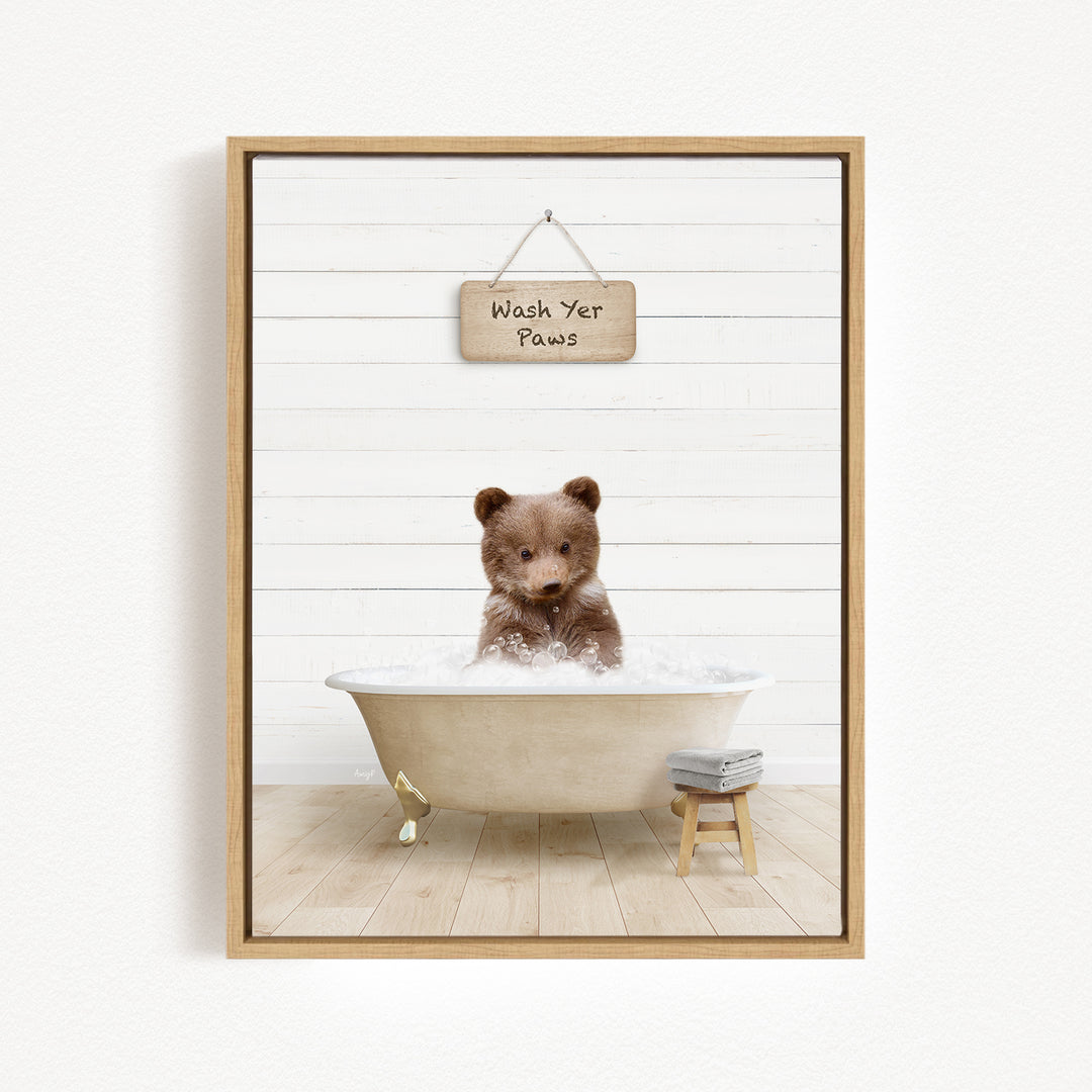 A cute brown bear sitting in a bathtub filled with water, with a sign above that says "Wash Your Paws".