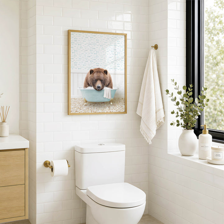 a bathroom with a white toilet, a framed picture of a bear in a bathtub, and a towel hanging on the wall.