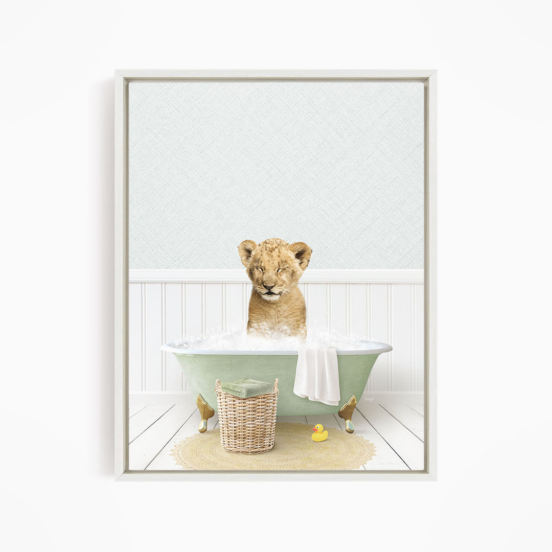 A young lion cub sitting in a green bathtub filled with bubbles, surrounded by a yellow rubber duck and a basket.