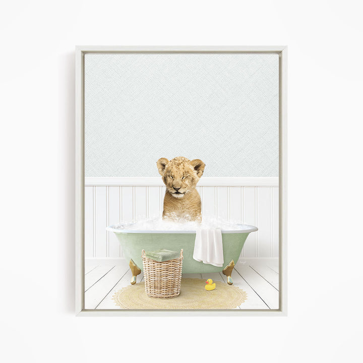 A young lion cub sitting in a green bathtub filled with bubbles, surrounded by a yellow rubber duck and a basket.