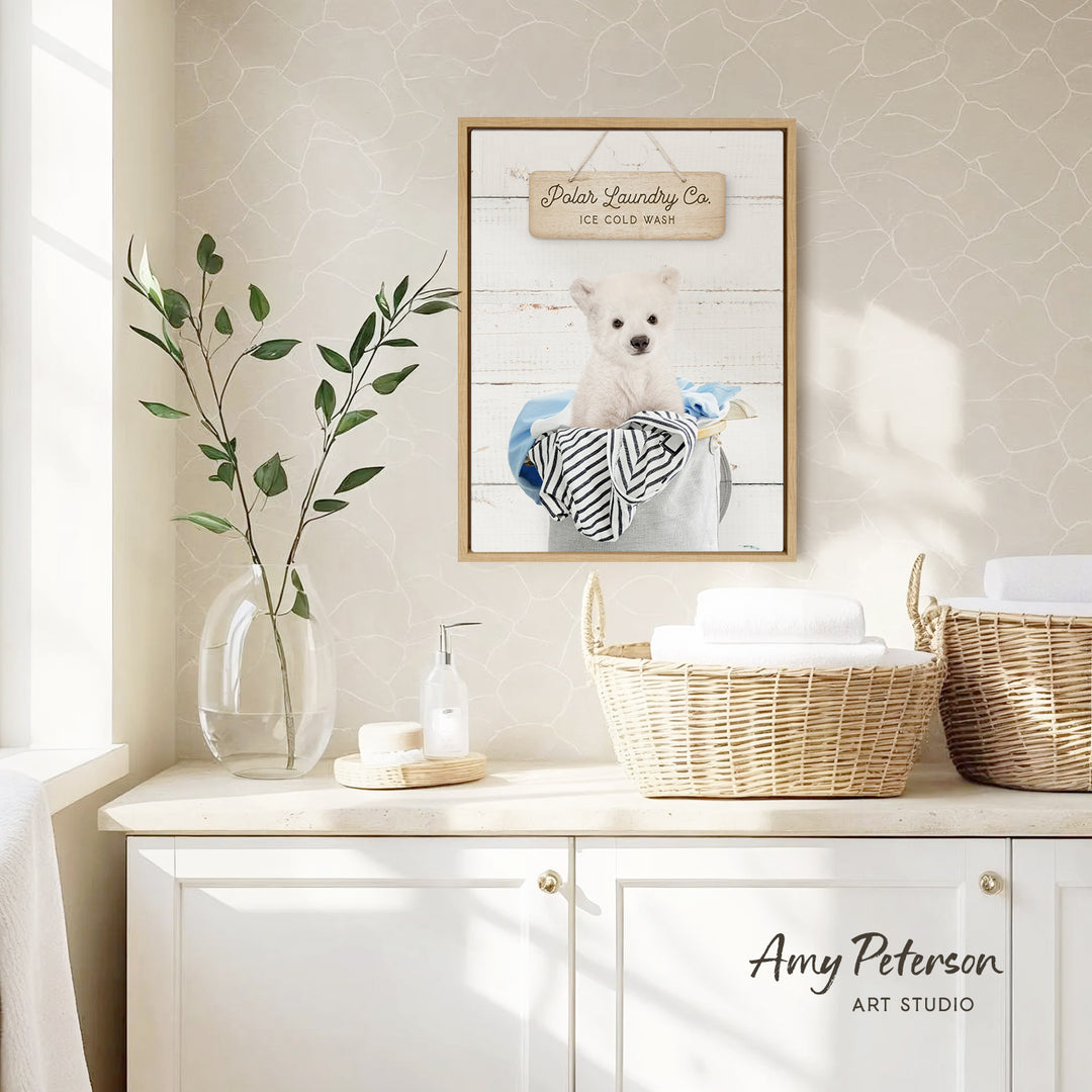 a framed picture of a polar bear sitting in a basket, hanging on a wall above a white cabinet with baskets.