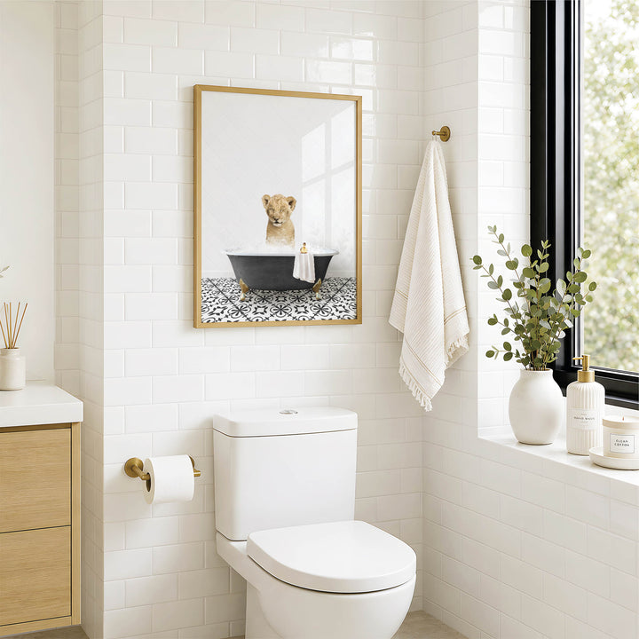 A modern bathroom with a white toilet, a framed picture of a lion in a bathtub, and a window with greenery on the sill.