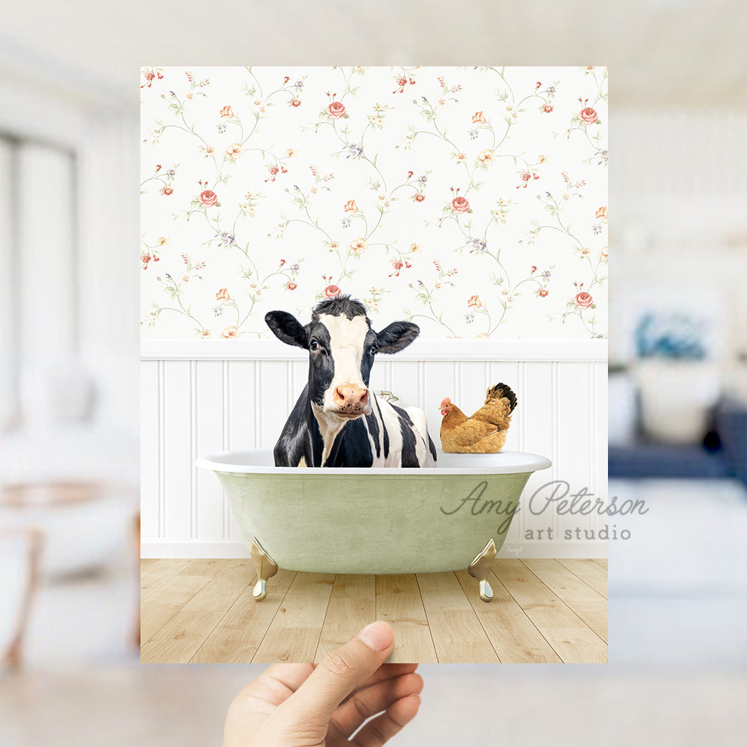 a hand holding up a photo of a cow in a bathtub