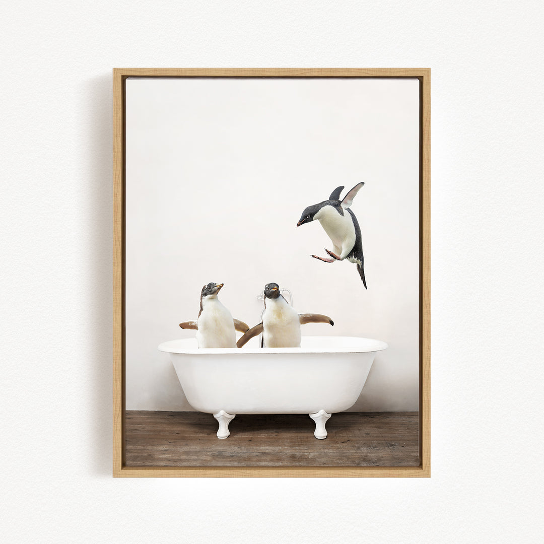 A framed image depicting two penguins sitting in a white bathtub, with one penguin flying towards the other.