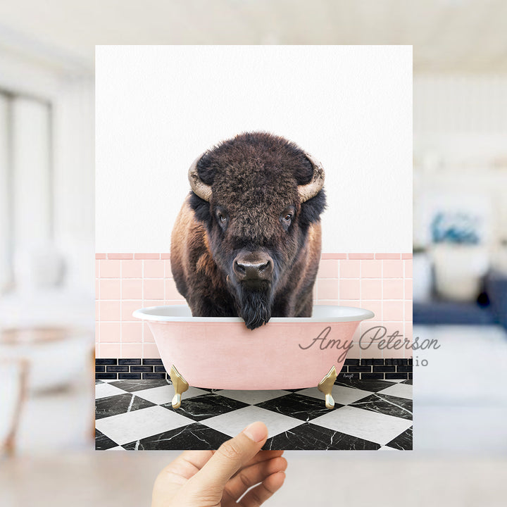 a person holding up a picture of a bison in a bathtub