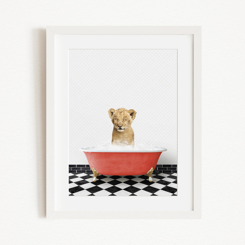 A young lion cub sitting in a red bathtub filled with water, surrounded by a black and white checkered floor.