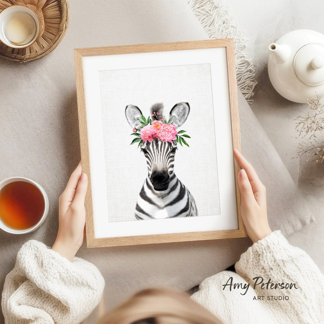 A person is holding a framed picture of a zebra with a floral headpiece, surrounded by various objects such as a teapot, a cup, and a bowl.