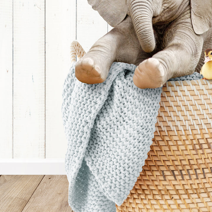 a stuffed elephant sitting on top of a basket