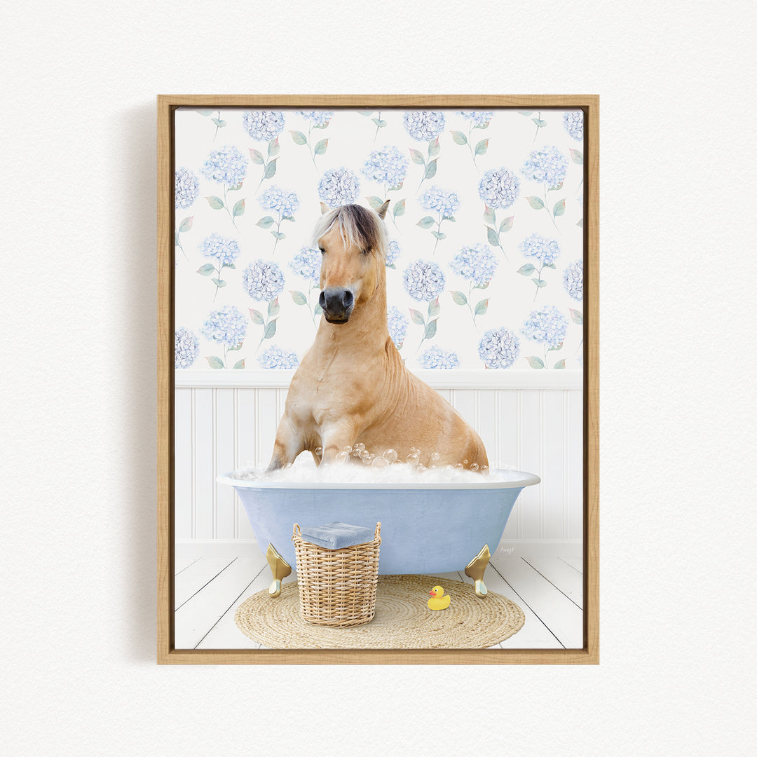 A light brown horse is sitting in a blue bathtub filled with water, surrounded by a wicker basket and a yellow rubber duck.