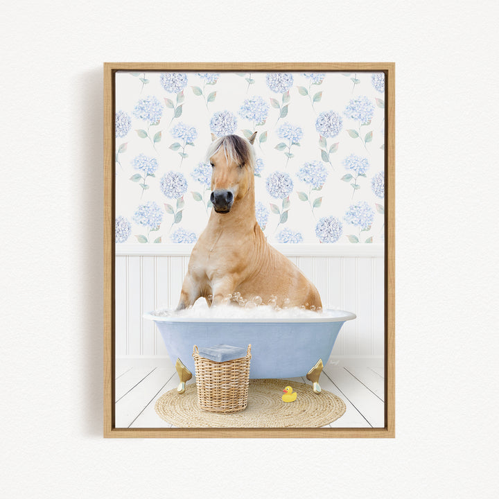 A light brown horse is sitting in a blue bathtub filled with water, surrounded by a wicker basket and a yellow rubber duck.