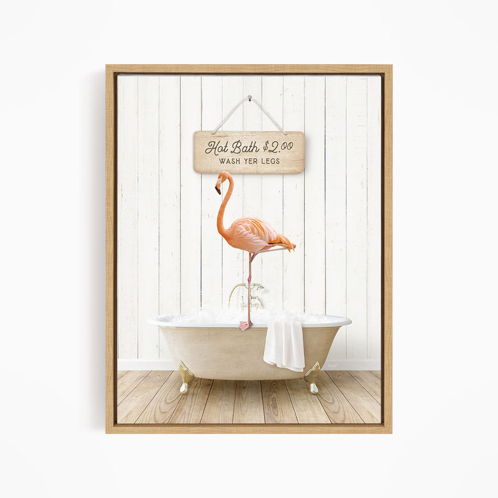 A framed image of a pink flamingo standing on a white bathtub, with a wooden sign above it that reads "Hot Bath $2.00 WASH YOUR LEGS".
