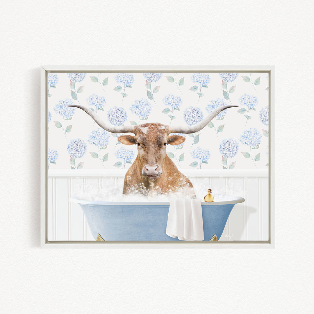 A brown cow with large horns is sitting in a blue bathtub filled with water, surrounded by a floral pattern on the wall behind it.
