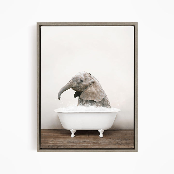 A baby elephant sitting in a white bathtub filled with water, appearing to enjoy the bath.