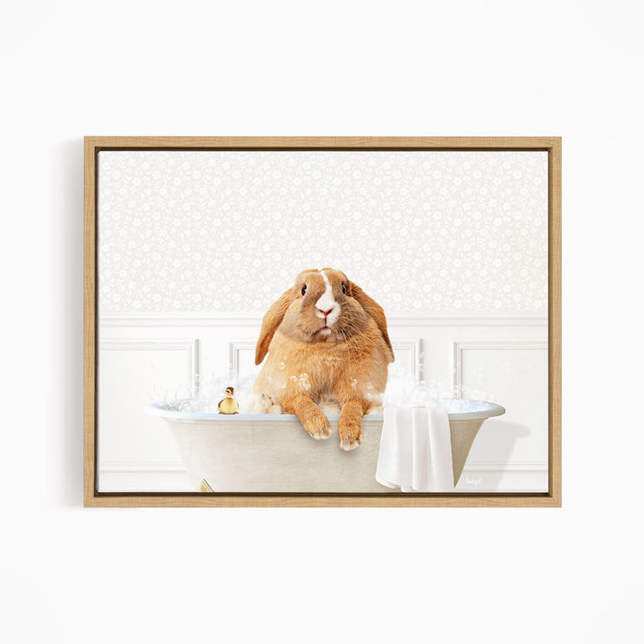 A brown rabbit sitting in a bathtub filled with water, with a towel and a small toy nearby.