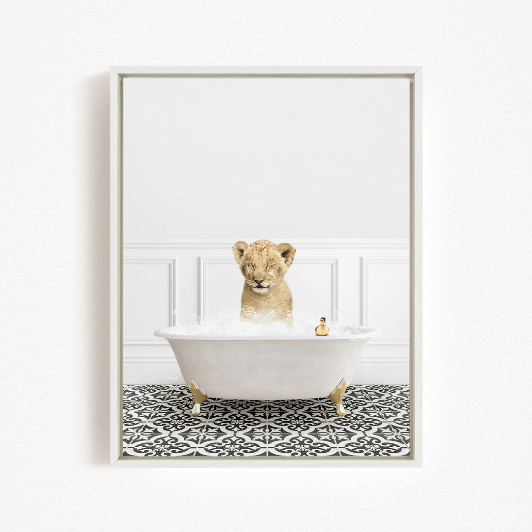 A young lion cub sitting in a white bathtub filled with bubbles, surrounded by a black and white patterned floor.