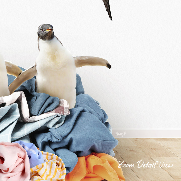 A penguin standing on a pile of clothes, with a white wall in the background.