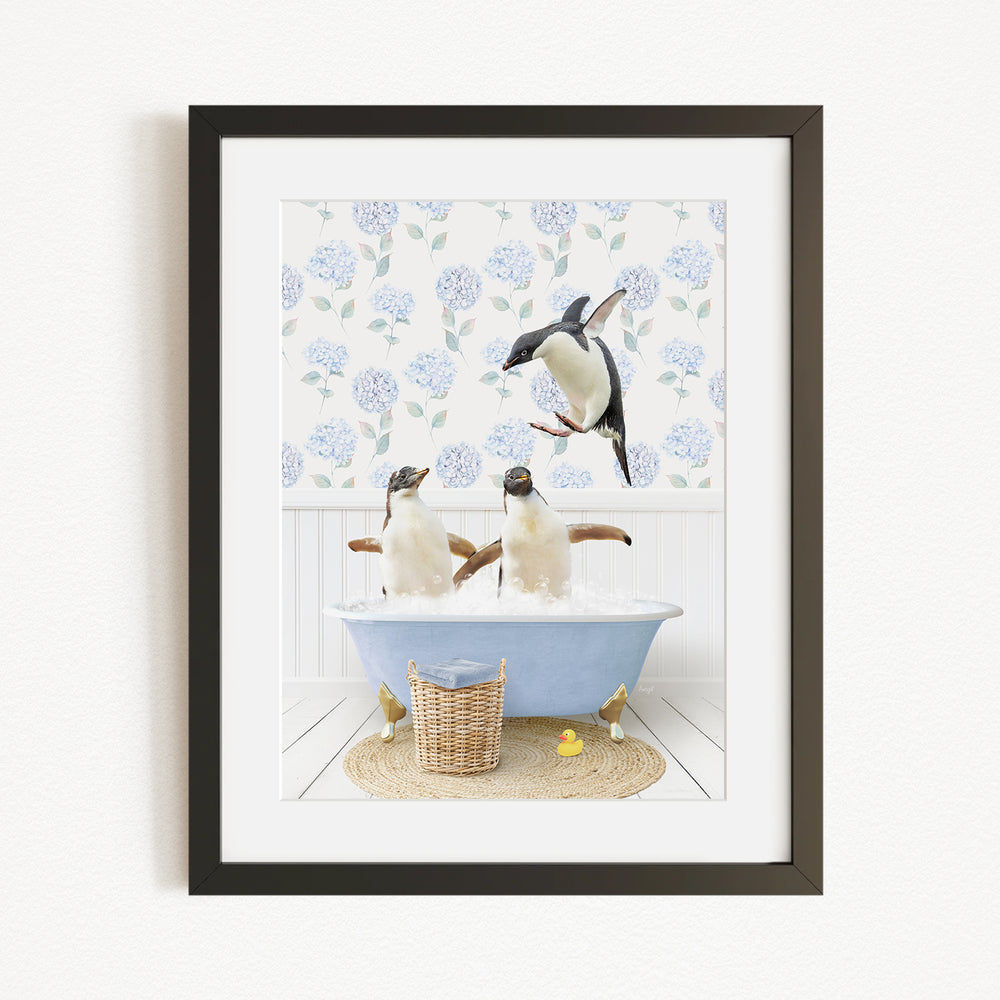 A framed image depicting two penguins sitting in a bathtub filled with bubbles, with one penguin standing on its hind legs and the other sitting comfortably.