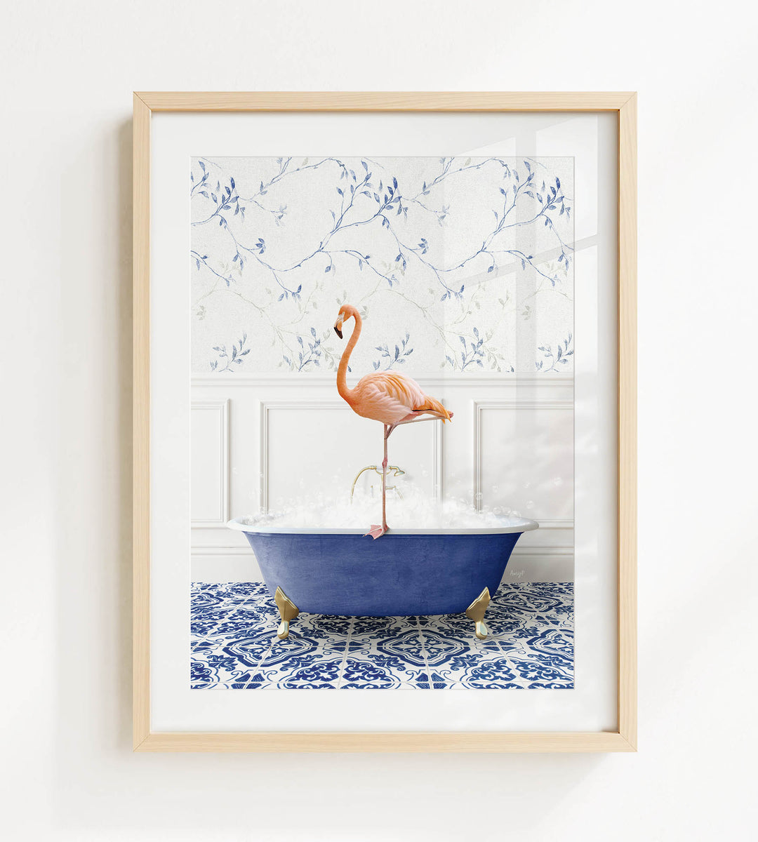 A framed image depicting a pink flamingo standing on the edge of a blue bathtub filled with bubbles, set against a blue and white floral wallpaper background.