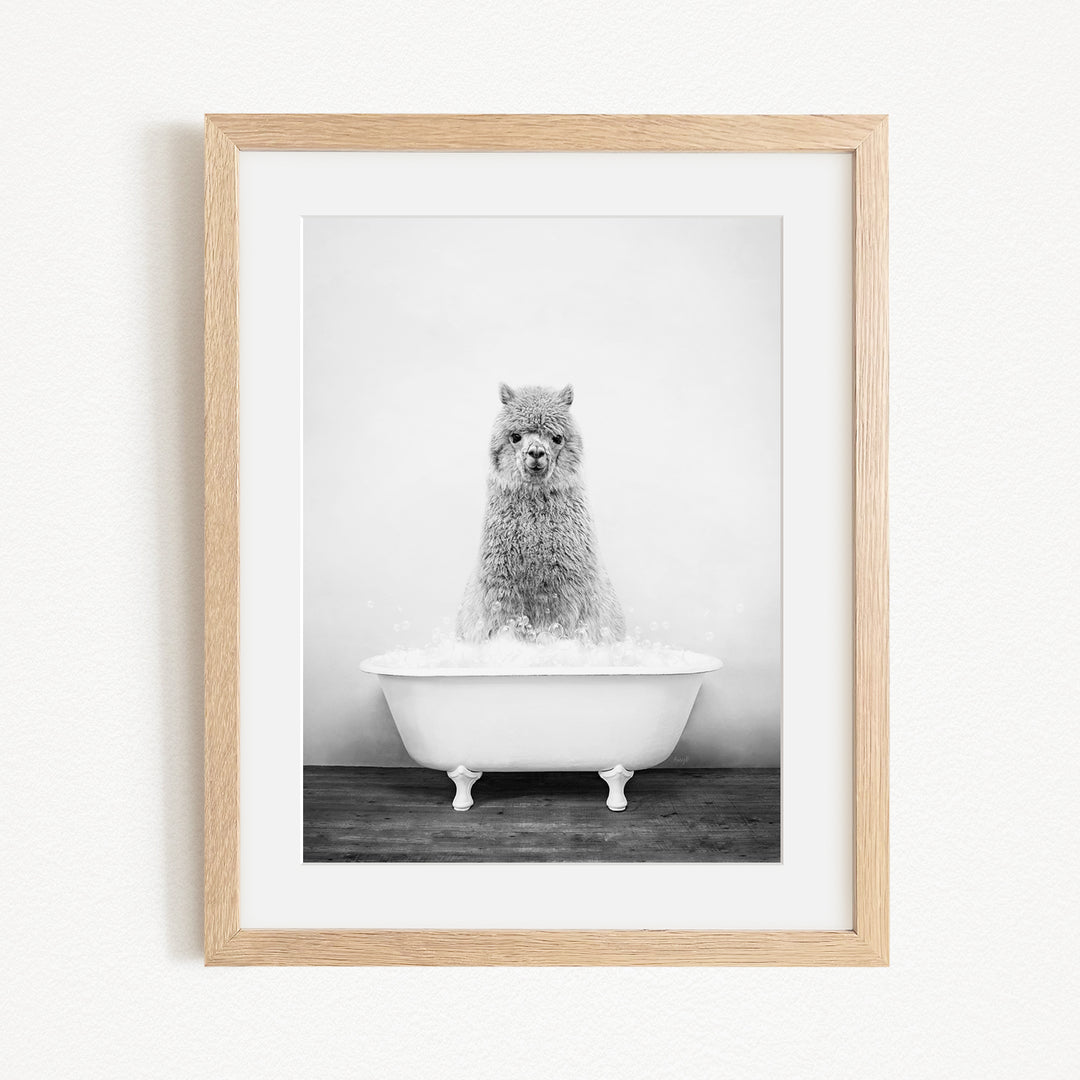 A black and white image of a fluffy, furry animal, possibly a dog or a cat, sitting in a white bathtub filled with water.