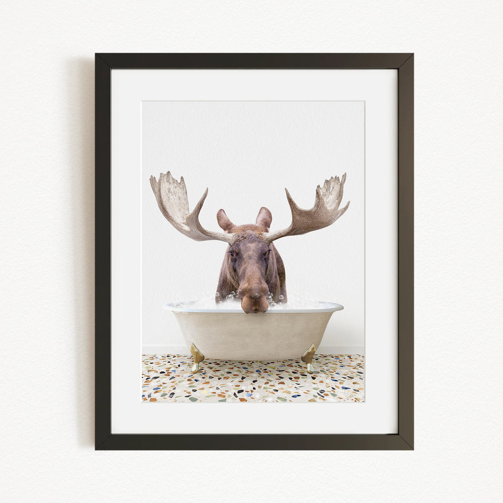 A moose with large antlers is sitting in a bathtub, with its head submerged in the water.