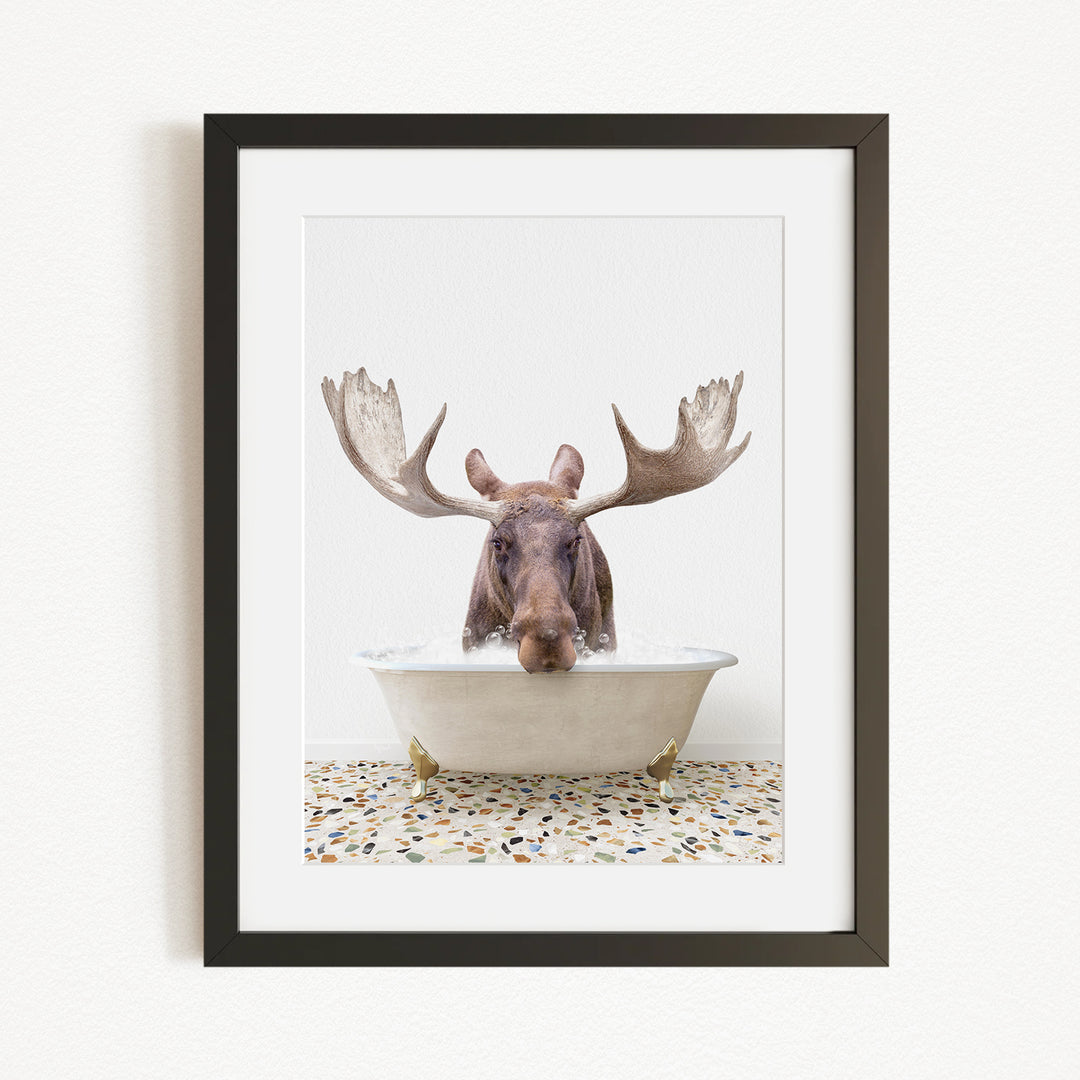 A moose with large antlers is sitting in a bathtub, with its head submerged in the water.