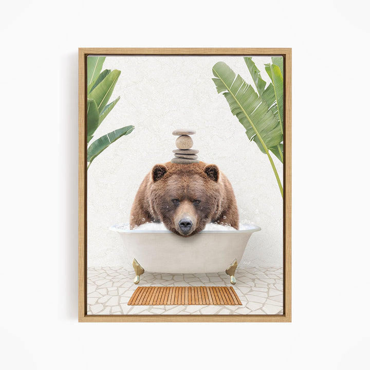 A brown bear is sitting in a white bathtub filled with water, surrounded by green leaves and a wooden mat on the floor.