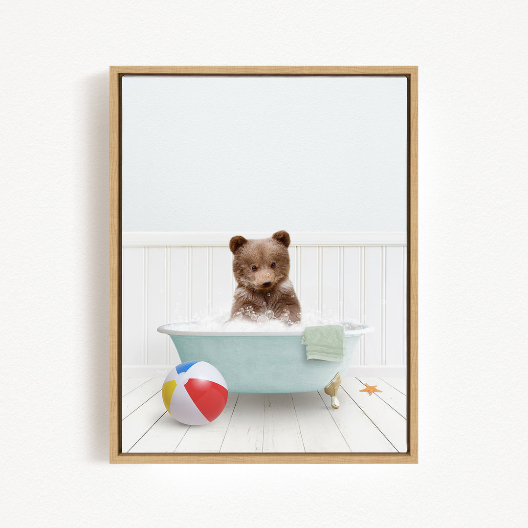 A brown bear sitting in a blue bathtub filled with bubbles, surrounded by a beach ball and a towel.