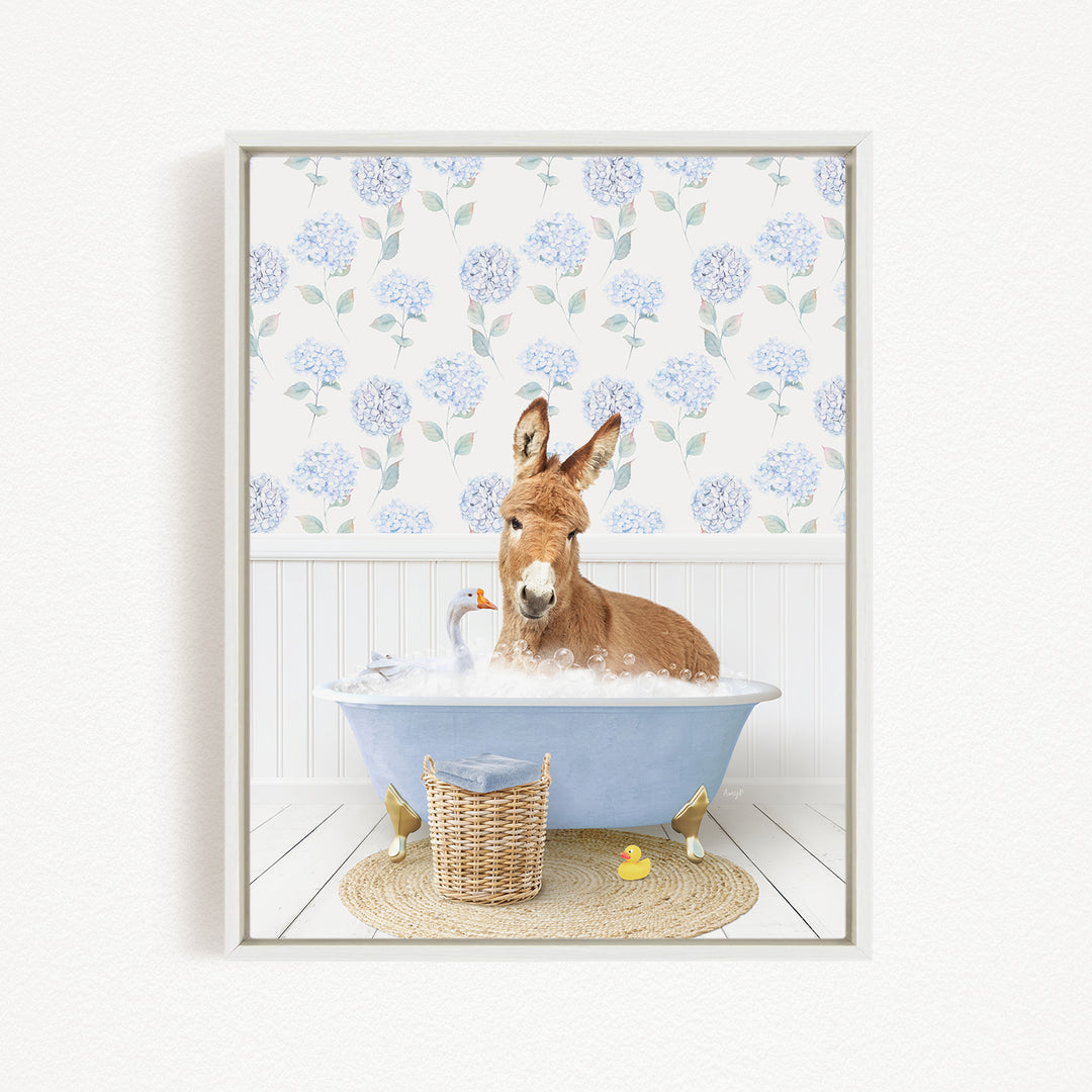 A donkey is sitting in a blue bathtub filled with bubbles, surrounded by a wicker basket and a rubber duck.