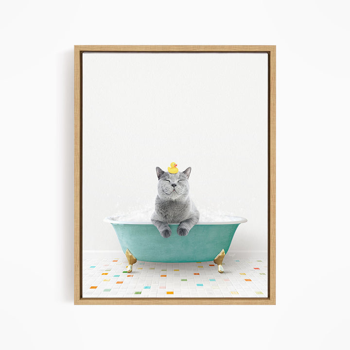 A gray cat sitting in a green bathtub, with a yellow rubber duck perched on its head.