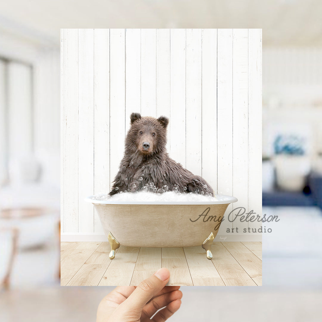 a hand holding a photo of a bear in a bathtub