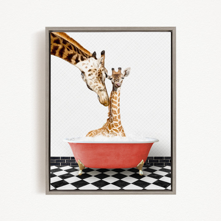 A mother giraffe and her baby giraffe are sitting together in a red bathtub, with the mother gently licking her baby.
