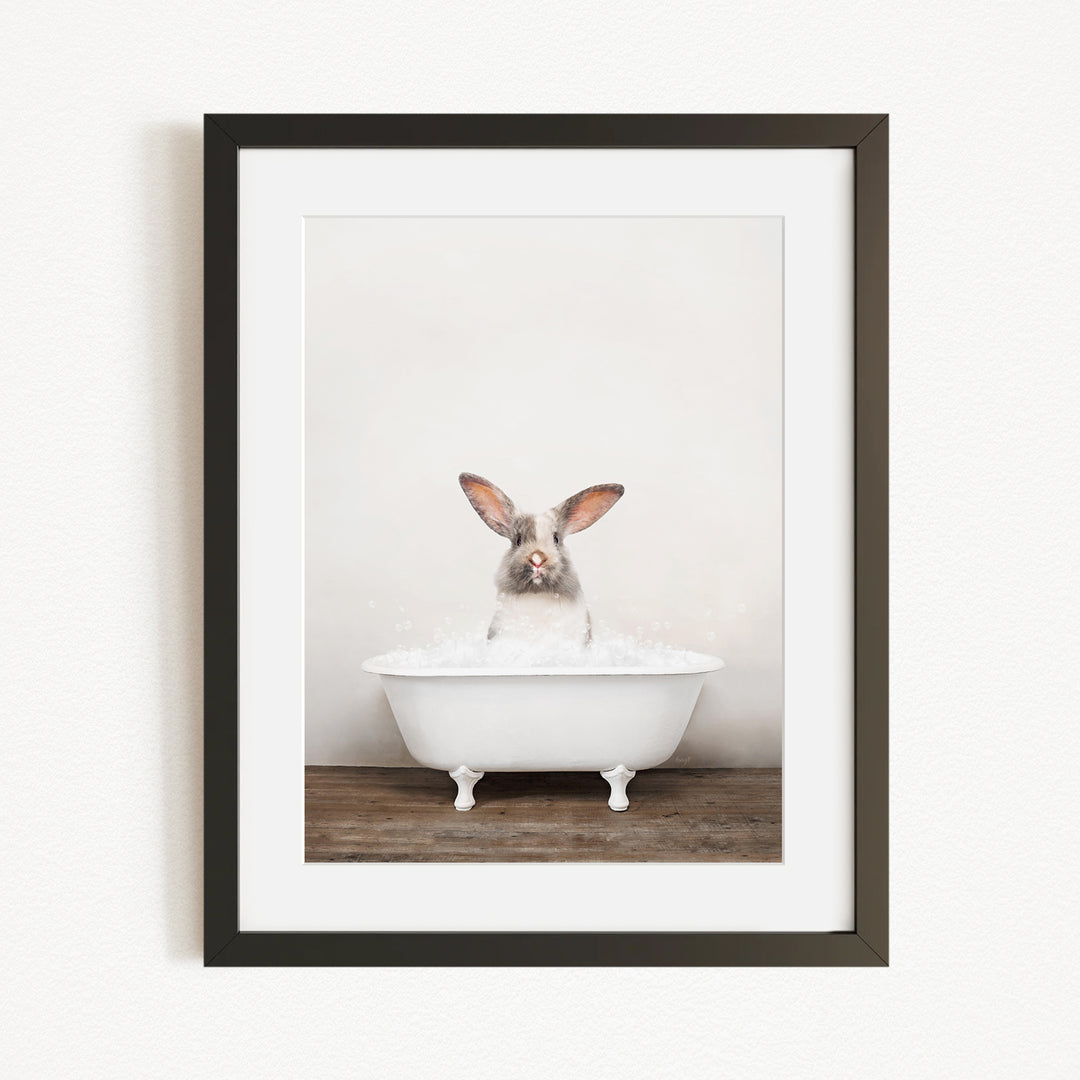 A white rabbit sitting in a white bathtub filled with water, looking directly at the camera.