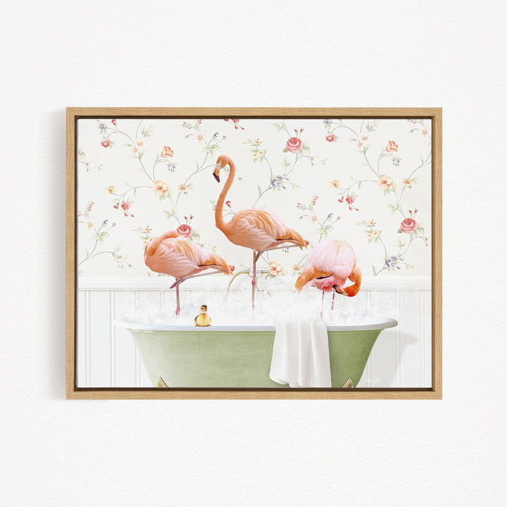 A framed print depicting three pink flamingos standing in a green bathtub, with a floral pattern on the wall behind them.